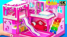 a hand holding a pink doll house with a slide in it's center and stairs leading up to the bed