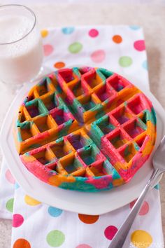 a waffle on a plate with a glass of milk next to it and a polka dot napkin