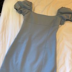 a blue dress laying on top of a white bed