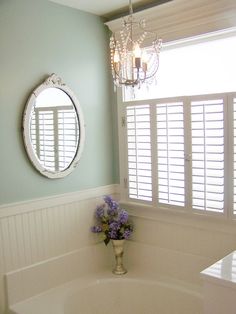 a white bath tub sitting next to a window with shutters on the windowsill