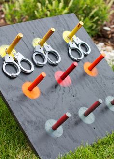 a wooden board with scissors and pegs on it in the middle of some grass