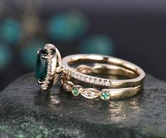 two gold wedding rings with green and white stones