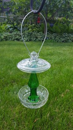 a green glass bird feeder in the grass