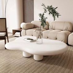 a living room filled with furniture and a plant in a vase on the coffee table