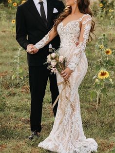 a bride and groom standing in front of sunflowers with their arms around each other