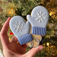 two decorated cookies in the shape of mittens and snowflakes on a christmas tree