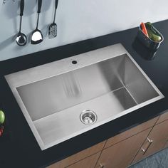 a stainless steel kitchen sink with utensils on the countertop and in front of it