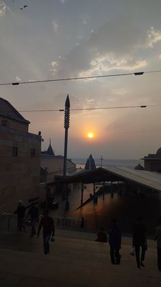 people are walking on the boardwalk at sunset