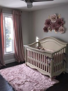 a baby's room decorated in pink and gray with floral decorations on the wall