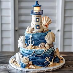 a three tiered cake decorated with seashells and a light house on top