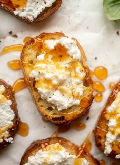 toasted bread topped with cheese and sauce on a white surface next to basil leaves