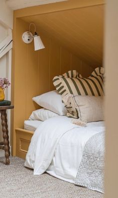 a bed with white sheets and pillows next to a table with vases on it