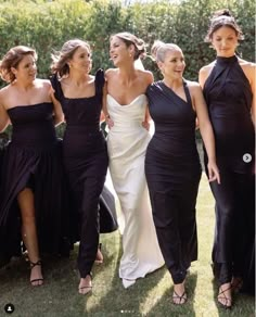 bridesmaids in black dresses walking together on the lawn at an outdoor wedding ceremony