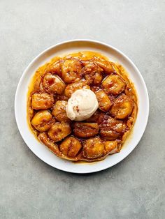 a white plate topped with bananas and ice cream on top of a gray countertop