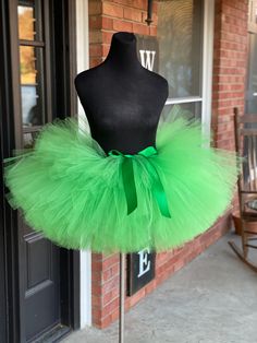 a mannequin wearing a green tutu in front of a brick building