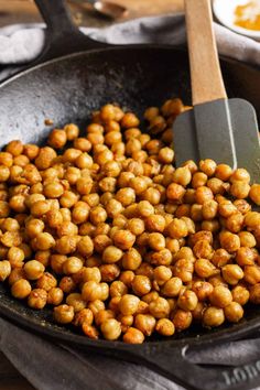 chickpeas being cooked in a skillet with a spatula on the side