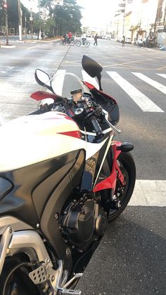 a red and white motorcycle parked on the side of the road next to a crosswalk