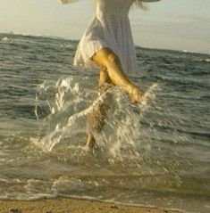 a woman is jumping into the water at the beach