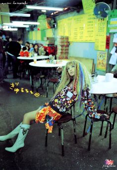 a woman sitting on top of a chair in a room filled with tables and chairs