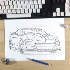 a drawing of a sports car on paper next to keyboard and computer keypads