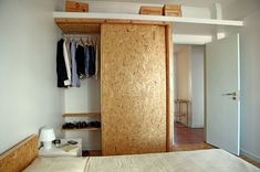 a bedroom with a bed, closet and clothes hanging on the wall next to it