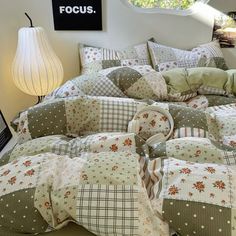 a bed covered in lots of pillows sitting next to a lamp on top of a table