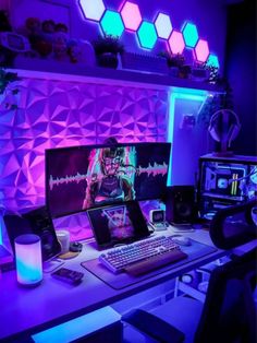 a computer desk with two monitors on it in front of a purple wall and blue lights