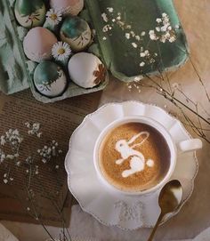 a cup of coffee sitting on top of a saucer next to eggs and flowers