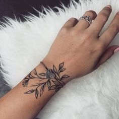 a woman's hand with a flower tattoo on her left wrist and the other arm