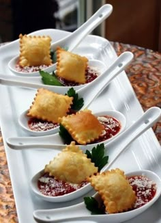 four small white dishes filled with food on top of a table