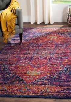 a colorful area rug in a living room with a chair and large window behind it