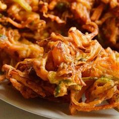 some fried food on a white plate with broccoli sprouts and sauce