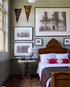 a bed sitting in a bedroom next to two pictures on the wall and a table