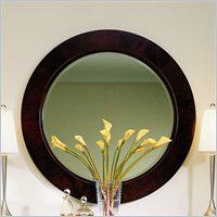 a round mirror sitting on top of a table next to a vase filled with flowers