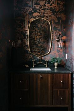 a bathroom sink with a mirror above it and wallpaper on the walls behind it