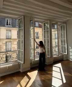 a woman standing in front of three large windows