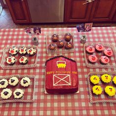 a table topped with cupcakes covered in frosting and farm animals on top of them