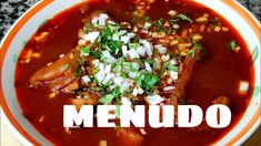 a white bowl filled with meat and vegetables on top of a granite counter next to the words menudo