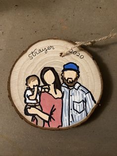 a wooden ornament with an image of a man and woman holding a baby