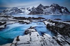 the mountains are covered in snow and blue water