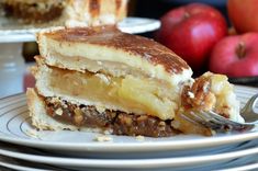 there is a piece of cake on the plate with a fork next to it and some apples in the background