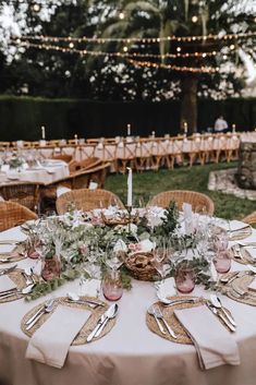 a table set up with place settings and flowers in vases on top of it