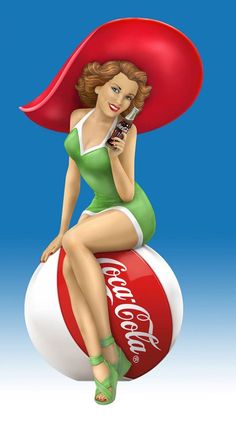 a woman sitting on top of a coca - cola ball with a cell phone in her hand