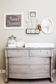 a baby's room with a dresser, mirror and pictures on the wall above it