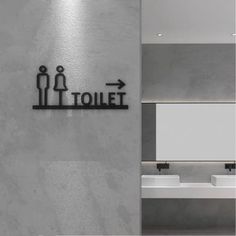 a bathroom with two sinks and a sign on the wall that says toilet above it