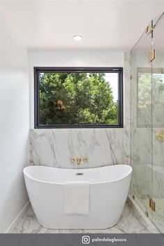 a white bath tub sitting under a window in a bathroom