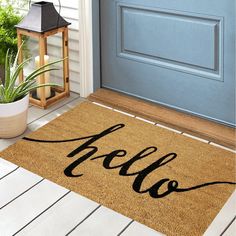 a welcome mat with the word hello on it in front of a blue door and potted plant