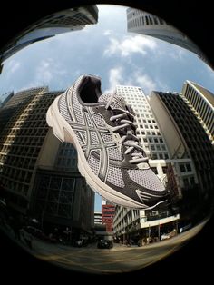 a pair of sneakers is seen through a fish eye lens in front of skyscrapers