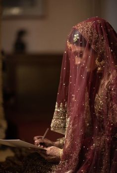 a woman in a red and gold bridal gown is holding a piece of paper