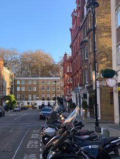 motorcycles are parked on the side of the road in front of some buildings and cars